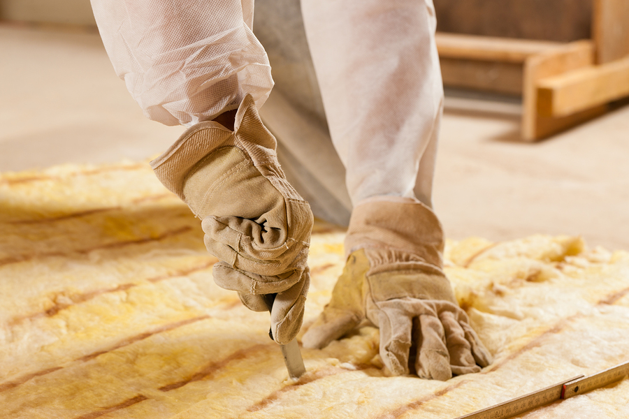 Man cutting insulation material for building Man - only hand to be seen - cutting some glass wool as material for thermal insulation of a new building
